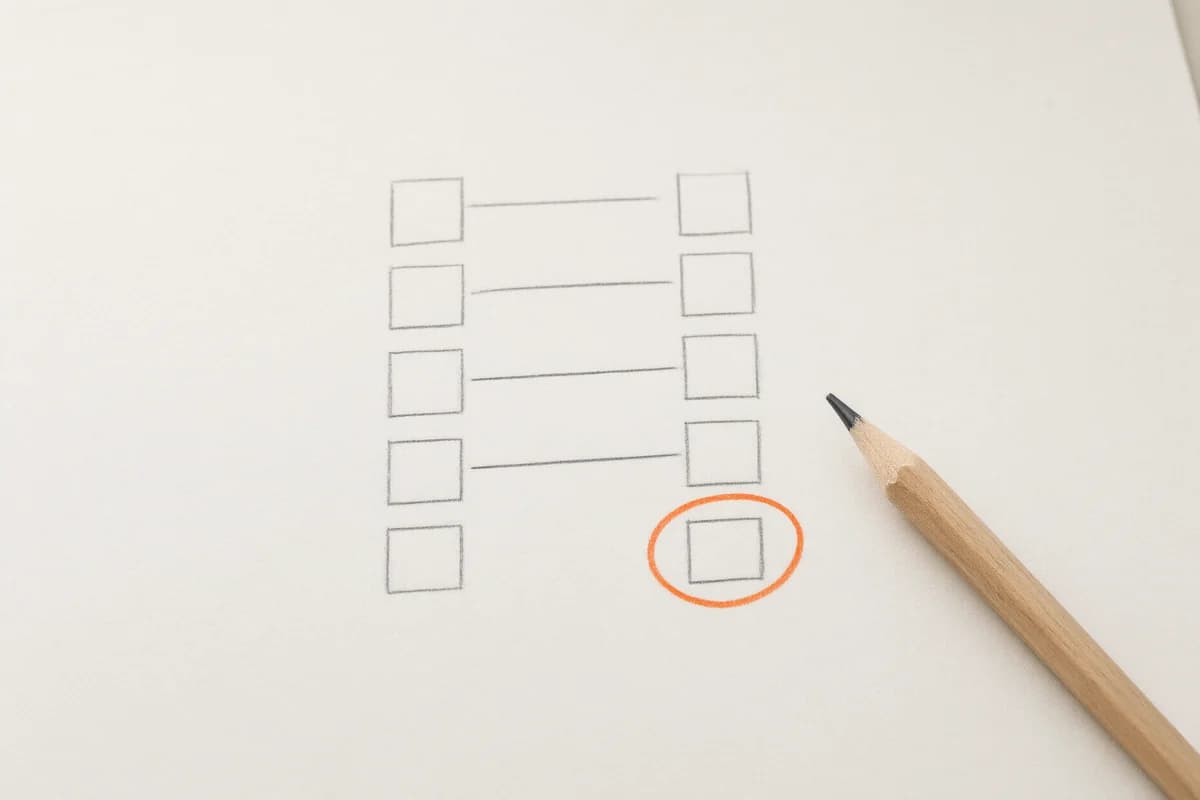 Close-up of a pencil sketch of 2 columns of boxes with lines matching pairs across the gap, one unmatched box circled in orange, a pencil at the edge
